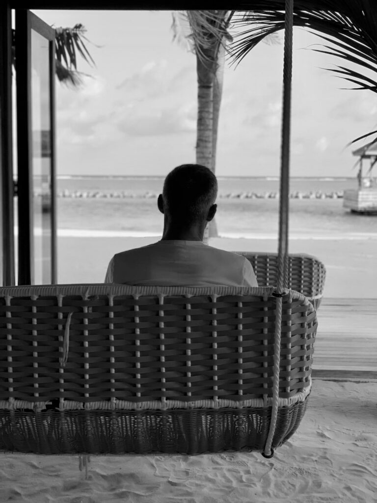 Man seen from behind on a swing seat facing the sea