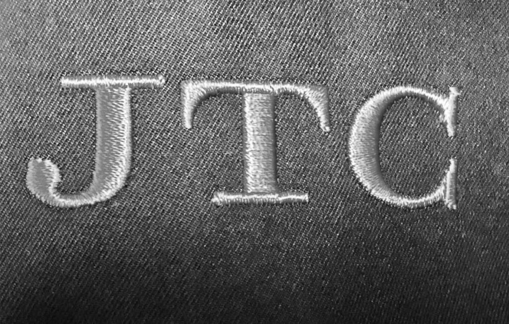 JTC logo embroidered on dark fabric
